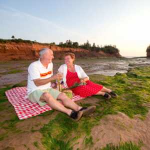 An elderly couple, enjoying a picnic on the Atlantic Ocean’s floor during low tides with a cliffs view of the Bay of Fundy at Burntcoat Head Park in Nova Scotia, Canada.