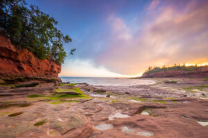 Panoramic view showing the Atlantic Ocean floor with tides flowing in and cliffs of the Bay of Fundy during sunset at Burntcoat Head Park in Nova Scotia, Canada.